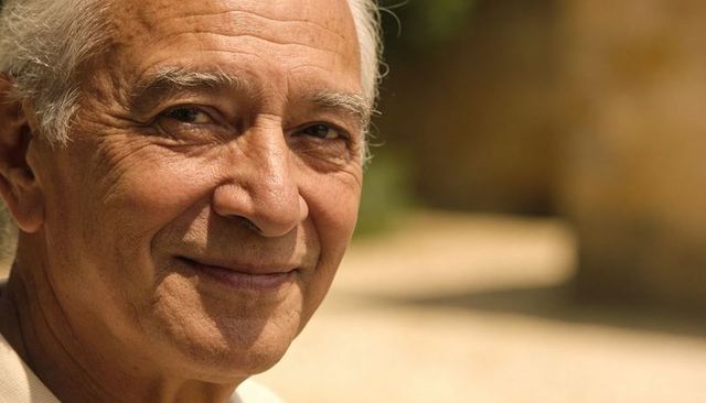 Smiling senior man in sunlit courtyard showing warm smile and gentle life-worn character