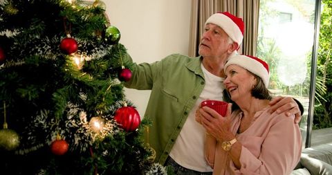 Senior Couple Decorating Christmas Tree in Festive Spirit