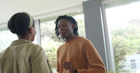 African american colleagues talking and gesturing by sunlit office windows, collaboration