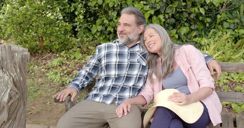 Senior Couple Relaxing on Bench in Serene Garden with Lush Greenery