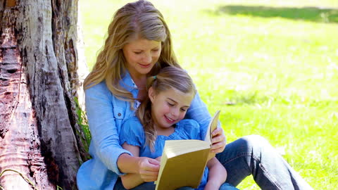 Mother and Daughter Reading Together in Park