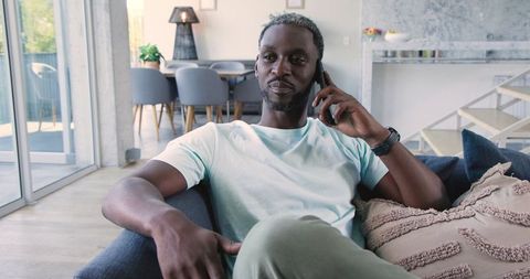 Relaxed man talking on smartphone in modern living room