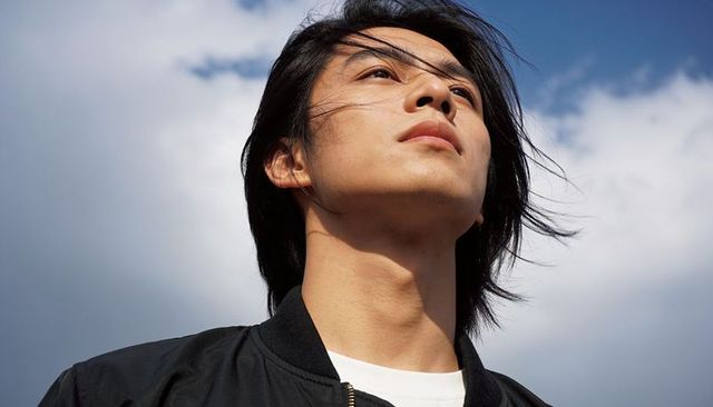 Gazing asian man looking upward at open sky, windblown hair, natural daylight headshot