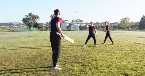 Cricket practice session with male teammates on sunny field