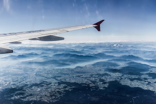 Aerial view from an airplane window showcasing a picturesque mountain range and landscape below. Ideal for travel blogs, airline advertisements, destination guides, tourism campaigns, and nature appreciation articles.