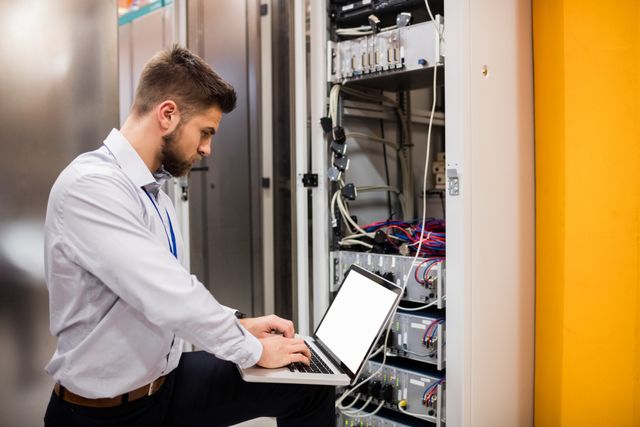Technician using laptop while analyzing server in server room