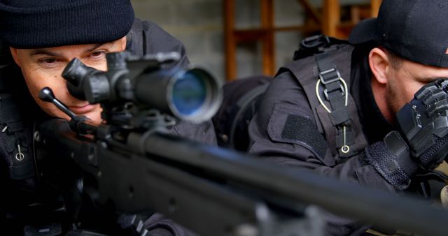 Two SWAT team members are in a tactical stance, one using a sniper rifle aiming through the scope and the other using binoculars. Ideal for topics relating to law enforcement training, tactical operations, police units, armed forces, security, and surveillance. Can be used for articles, blogs, and educational materials on military tactics and police procedures.