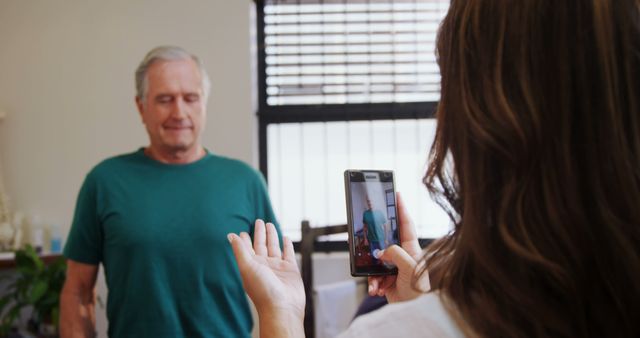 Woman Using Smartphone to Record Senior Man in Casual Setting - Download Free Stock Images Pikwizard.com