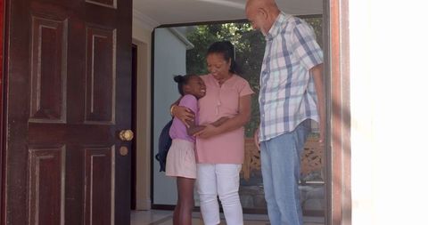 Grandparents Embracing Granddaughter on Sunny Entryway