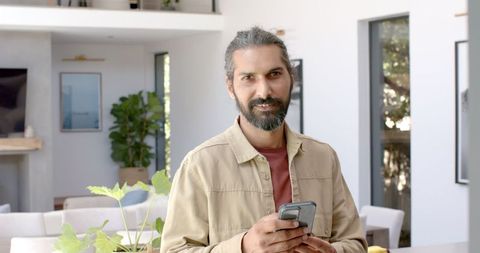 Man holding smartphone in modern home interior