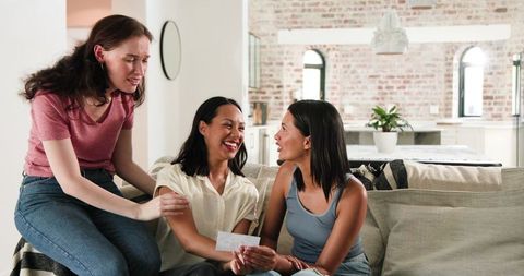 Excited diverse friends celebrating pregnancy with scan image