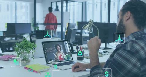 Businessman in Open-Plan Office Joining Virtual Meeting with Colleague