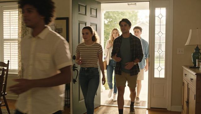 Friends entering sunlit home through front door, casual young adults walking into foyer