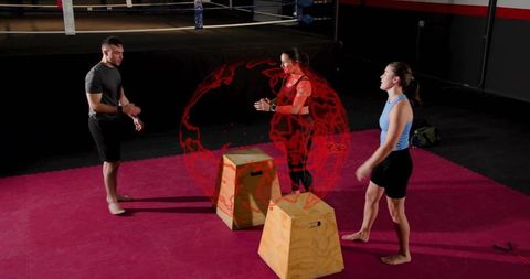 Coach guiding athletes through plyometric box drills in boxing gym with team focus