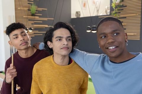 Multicultural male friends hanging out at pool table in modern lounge wearing sweaters
