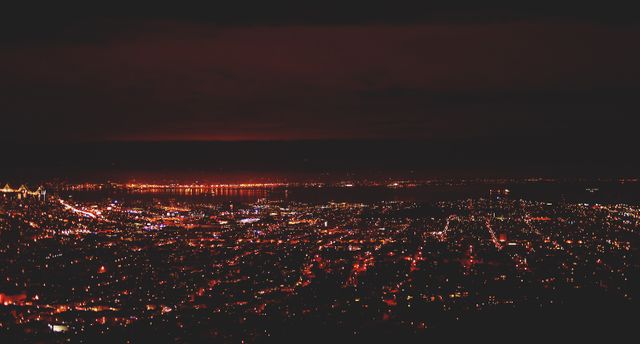 Picture displaying a city skyline at night, with buildings and streets illuminated by red and orange lights. Suitable for use in travel brochures, cityscape backgrounds, night photography collections, and urban-themed designs.