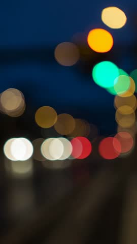 Urban night traffic lights creating colorful bokeh on wet road vertical video