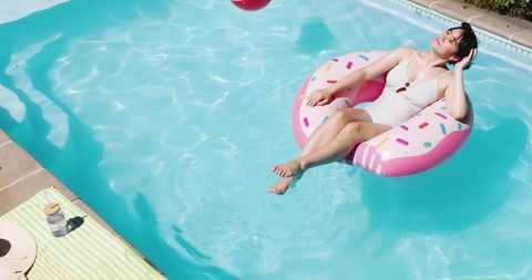 Woman Relaxing on Donut Float in Sunny Backyard Pool