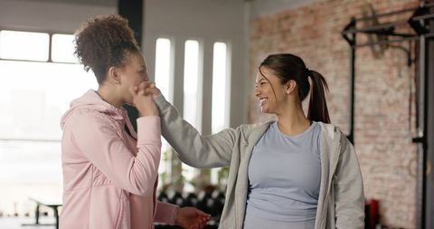 Diverse women exchanging fist bump in gym celebrating workout camaraderie