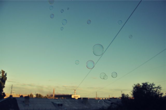 Soap bubbles float gently against a clear blue sky during sunset. Ideal for themes of tranquility, playfulness, and nature. Can be used for posters, calming backgrounds, or children’s playtime advertisements.