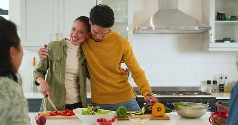 Smiling Friends Preparing Healthy Salad in Modern Kitchen