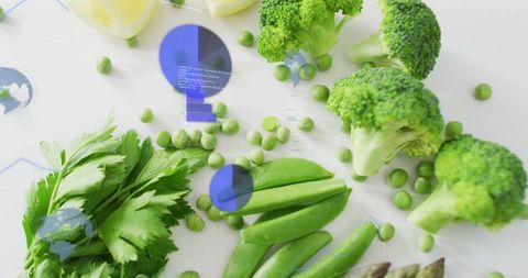 Arranging fresh green produce flatlay with broccoli peas parsley snap peas lemon accents
