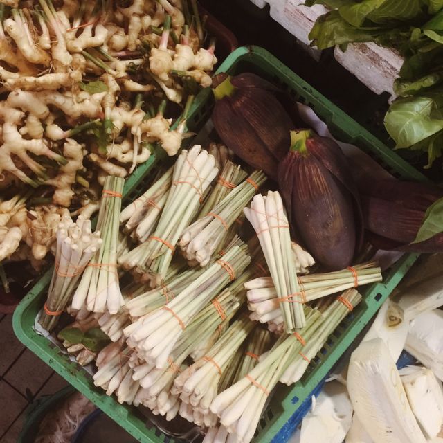 Fresh bundles of lemongrass, ginger roots and other vegetables arranged at a market stall. Ideal for food-related content, culinary blogs, articles about fresh produce, or health and nutrition topics.