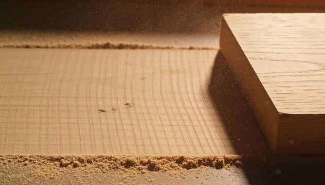Planed hardwood plank showing parallel tool marks, fresh sawdust and offcut block