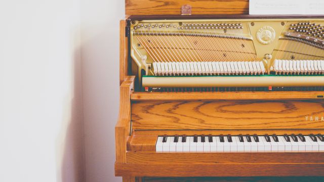 An upright piano with the lid open reveals the internal strings and wooden structure, along with the keys. This visual captures the craftsmanship of the instrument. Perfect for use in music education, advertisements for musical instruments, or home decor related to music.