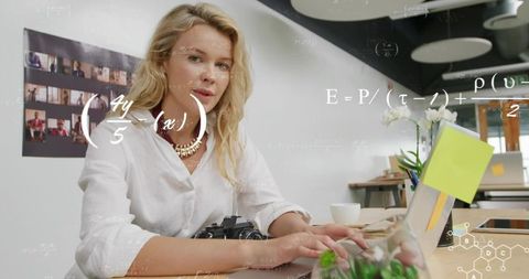 Woman typing on laptop generating animated science formulas in bright modern coworking studio