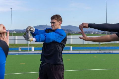 Teen soccer goalkeeper stretching on turf before training