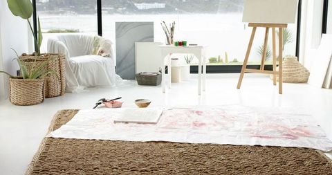 Coastal art studio with natural light featuring easel, brushes, paint-stained drop cloth