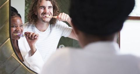 Couple Practicing Dental Hygiene Together in Bathroom