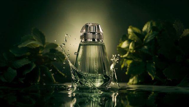 Emerald ribbed perfume bottle splashing in water with metallic cap and botanical luxe glow