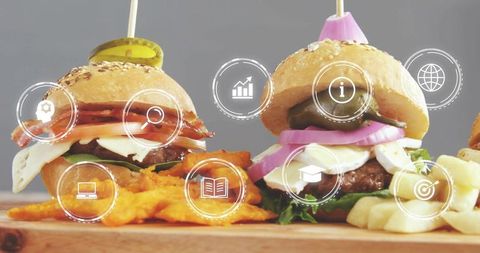 Mini sesame slider burgers serving with fries and crinkle chips on rustic wood board