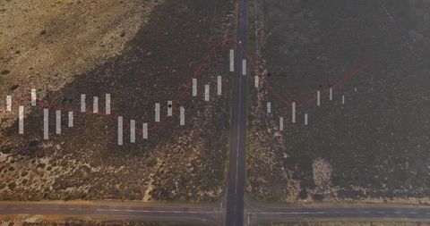 Aerial crossroads merging with candlestick market chart overlay across arid landscape
