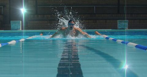 Male swimmer performing butterfly stroke in indoor pool competition