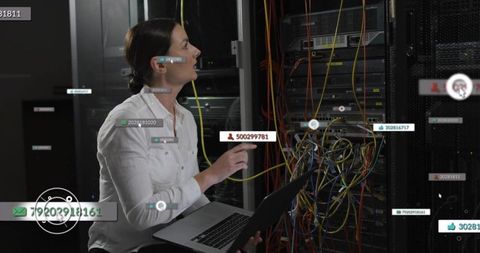 IT Technician Troubleshooting Server Rack with Laptop and Multicolor Network Cables