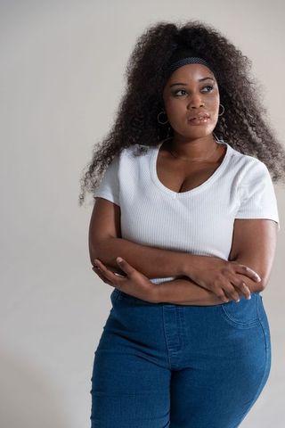 African american woman posing arms crossed wearing white top and denim