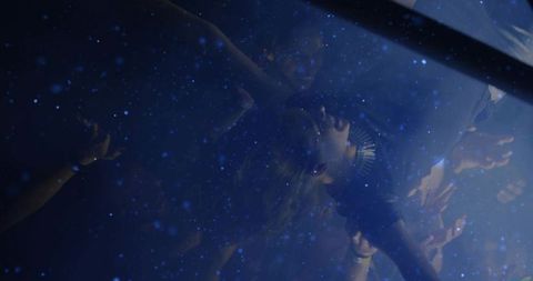 Crowd surfer with spiked necklace at concert with blue lights