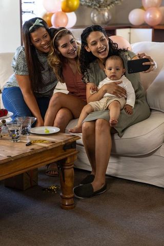 Diverse Friends Celebrating with Baby Boy Taking Selfie on Cozy Sofa