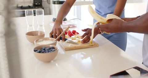 African american couple preparing fresh fruit on bright kitchen island