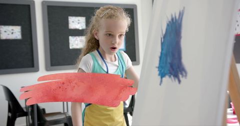 Young Girl Excitedly Painting in Classroom with Blue Brushstrokes - Download Free Stock Images Pikwizard.com