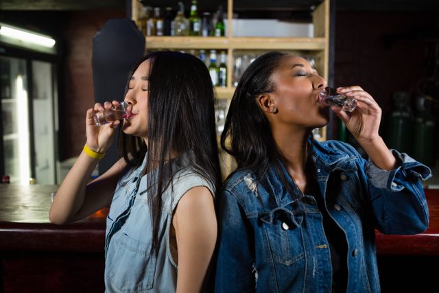 Female friends having tequila shot at bar counter
