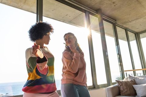 Dancing friends in seaside apartment enjoying sunlight and casual weekend morning