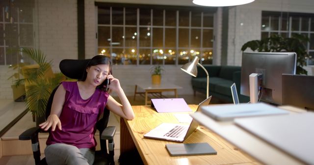 Young Woman Working Late in Office Talking on Phone and Using Laptop - Download Free Stock Images Pikwizard.com