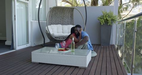 Happy couple relaxing on patio with drinks and fruit