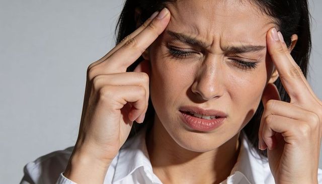 Woman pressing temples and showing migraine pain stress close-up professional portrait
