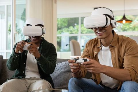 African american friends playing virtual reality games on living room sofa