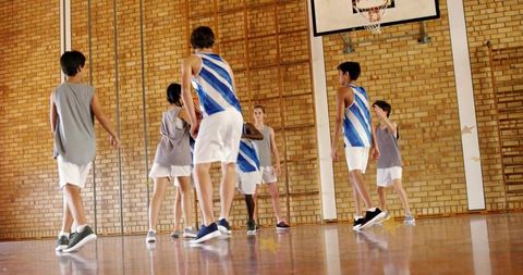 Youth basketball team practicing in school gym, moving toward hoop, teamwork action